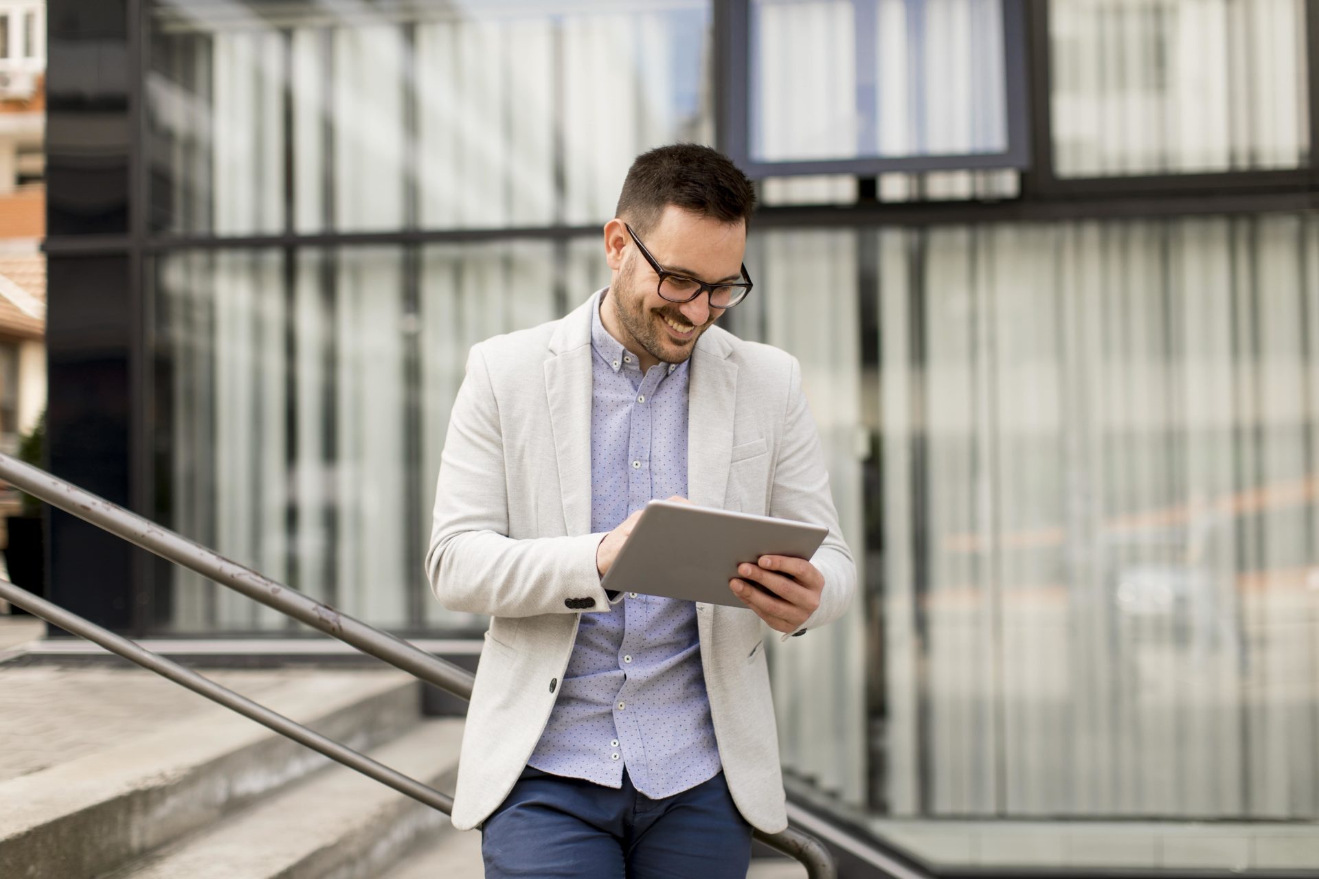 handsome-young-businessman-with-digital-tablet-by-office-building-min