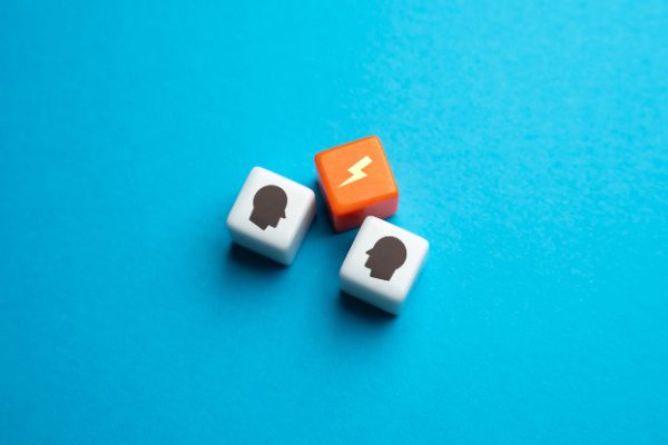 Trois dés sur fond bleu, deux blancs avec des silhouettes de tête et un orange avec un éclair.
