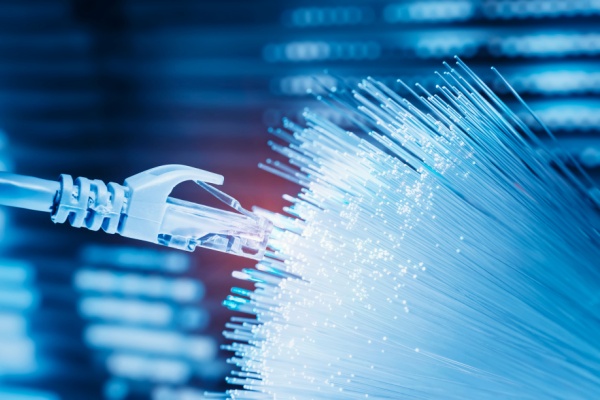 Câble réseau connecté à des fibres optiques lumineuses, illustrant le raccordement en fibre optique.