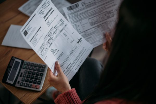 Une personne examine un modèle de bulletin de paie avec une calculatrice sur une table en bois.