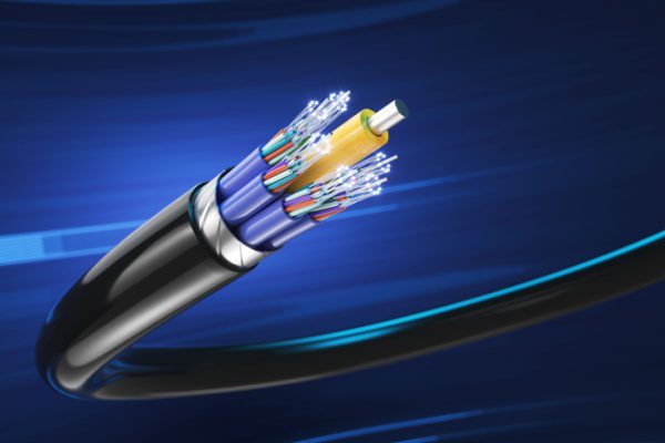 Fibre optique colorée en gros plan sur fond bleu, représentée avec divers brins et une gaine protectrice noire.
